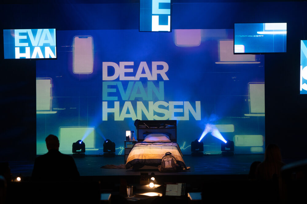 A set lit in blue, screens and a single bed centre stage